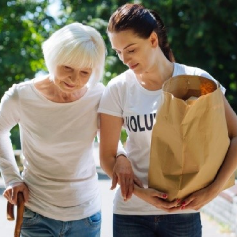 Female volunteer helping senior orphan with groceries